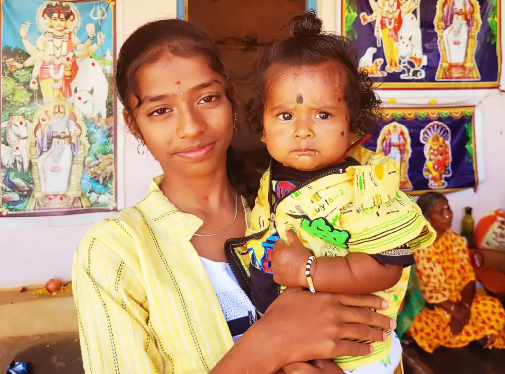 Junge indische Mutter mit ihrem Kind auf dem Arm.