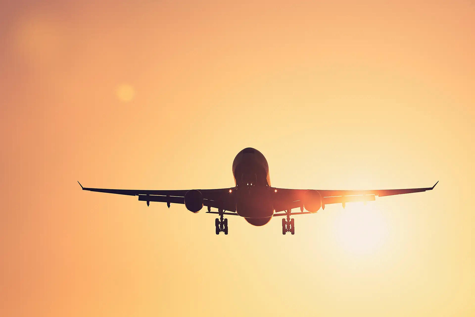 Flugzeug in der Luft und im Hintergrund die untergehende Sonne.